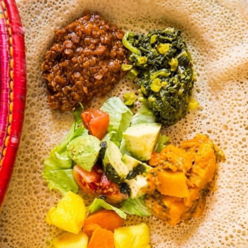 Ethiopian injera bread with various colorful stews, vegetables, and fruit, next to a woven basket.
